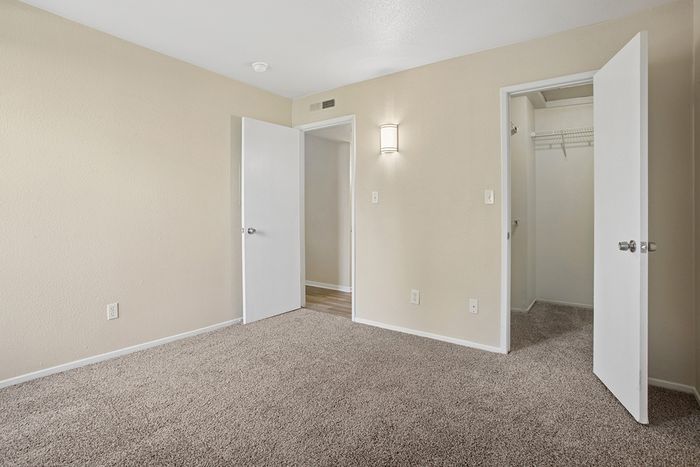 Inviting bedroom with plush carpet, soft beige walls, and convenient walk-in closet.