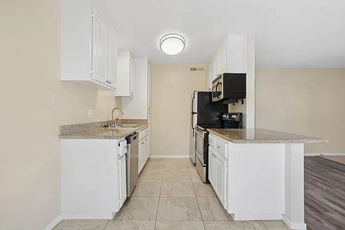 Modern kitchen with sleek granite countertops, stainless steel appliances, and spacious white cabinetry.