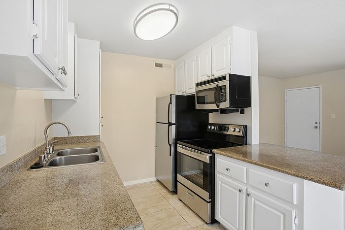 Modern kitchen with elegant granite countertops, stainless steel appliances, and crisp white cabinetry.