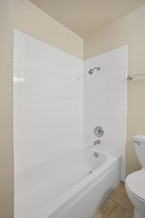 Modern bathroom with a pristine white bathtub, elegant tile surround, and sleek fixtures.