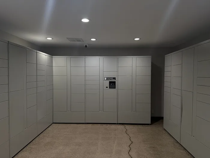 Modern package locker room with sleek gray lockers and advanced digital technology, ensuring secure and efficient parcel delivery.