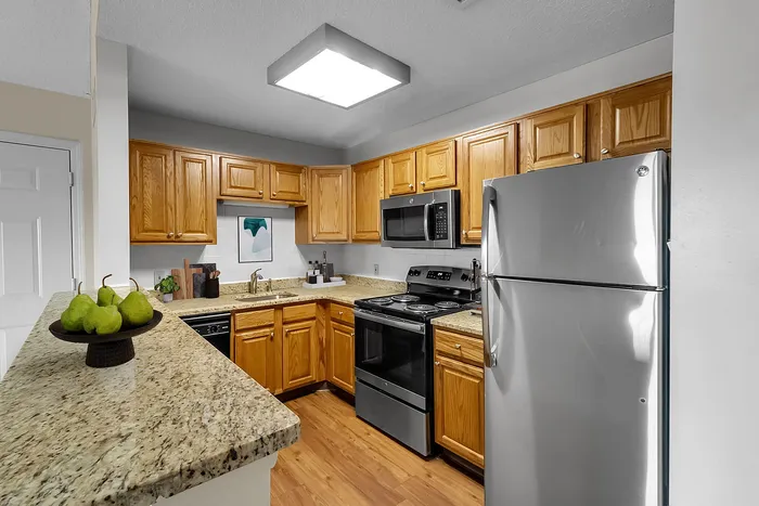 Modern kitchen with stainless steel appliances, granite countertops, and warm wooden cabinetry, perfect for culinary enthusiasts.