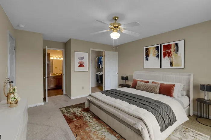 Elegant bedroom featuring cozy bedding, chic artwork, and a spacious walk-in closet, perfect for a serene retreat.