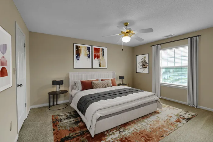 Elegant bedroom with modern decor, featuring a plush bed with stylish pillows, artistic wall prints, and a vibrant patterned rug.