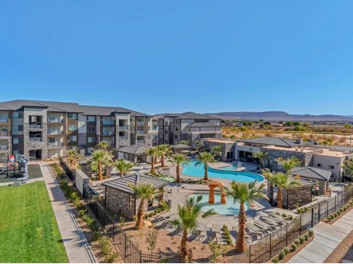 1-Bedroom Apartments in St. George, UT - Grayhawk at River's Edge - Aerial View of The Luxurious Pool Area Surrounded By Palm Trees and Modern Housing