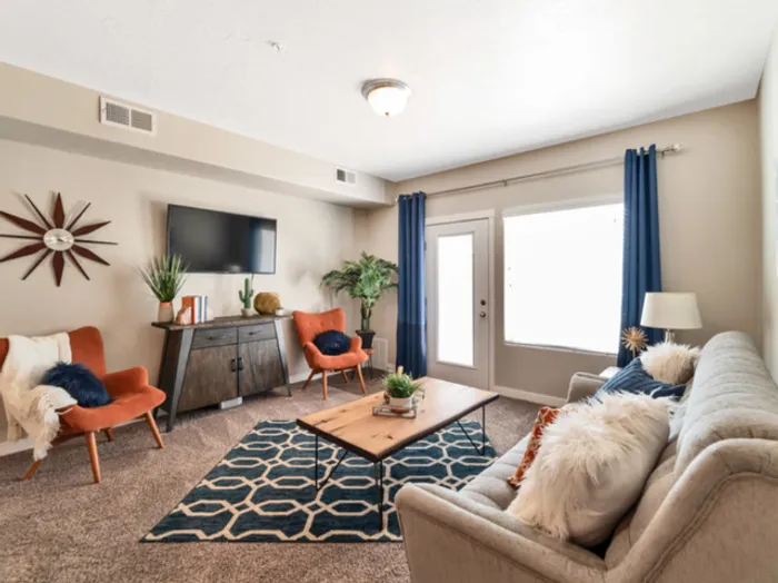 Living room with couch, coffee table, flat screen television, 2 chairs, and console table