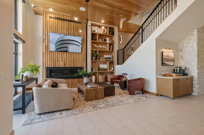 Apartments with Attached Garage in American Fork, UT - Elevate at 620 - Waiting Area with Couch, Stools, Armchairs, Display Shelves, and Bright Lighting.