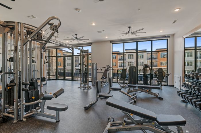 Apartments in American Fork, UT with In-Unit Washer and Dryer - Elevate at 620 - 24-Hour Fitness Center with Ceiling Fans, Cable Machine, Workout Benches, Full-Body Mirrors, and Floor-to-Ceiling Windows.