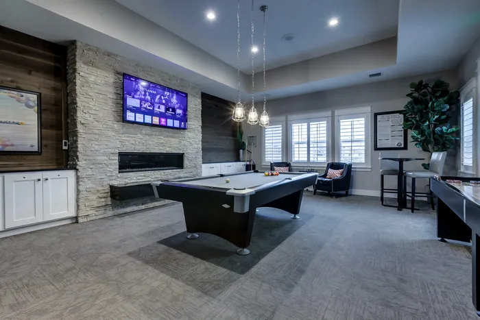 Game room with billiards table, shuffleboard, flat screen television, and fireplace