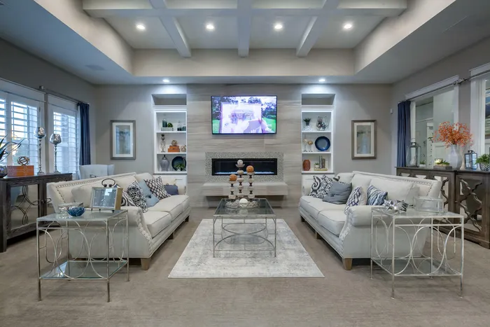 Clubhouse waiting room with 2 couches, flat screen television, fireplace, desk, 2 chairs, and coffee table