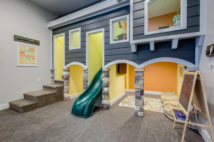 Playroom with 2 level playhouse with big slide and flat screen television