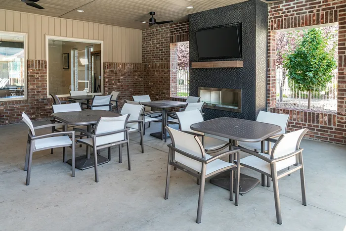 Chic outdoor seating area with modern tables and chairs, featuring a wall-mounted TV and stylish brick design.