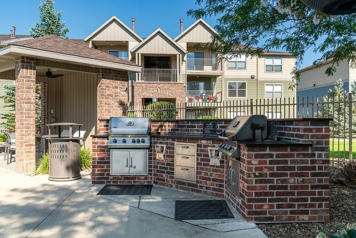 Charming outdoor communal space featuring stylish brick BBQ grills and cozy seating, perfect for gatherings in a serene residential setting.