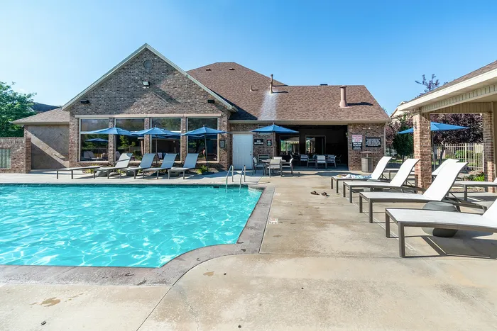 Inviting outdoor pool area with modern lounge chairs and shaded tables, perfect for relaxation and social gatherings.