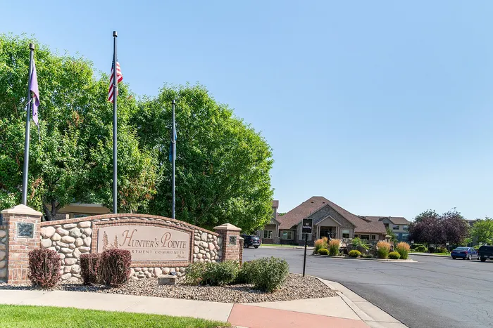 Charming Hunter’s Pointe entrance with stone accents, surrounded by lush greenery and a welcoming community feel.