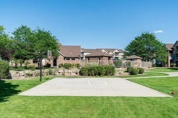 Charming apartment community with a lush green courtyard and a private basketball court, perfect for active living.