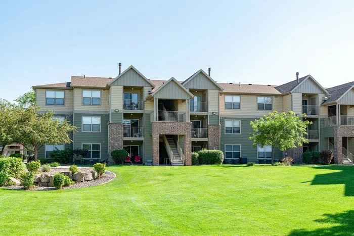 Charming apartment complex with lush green landscaping and spacious balconies.