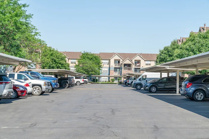 Inviting apartment complex with ample parking and lush greenery, featuring charming architecture and a serene atmosphere.