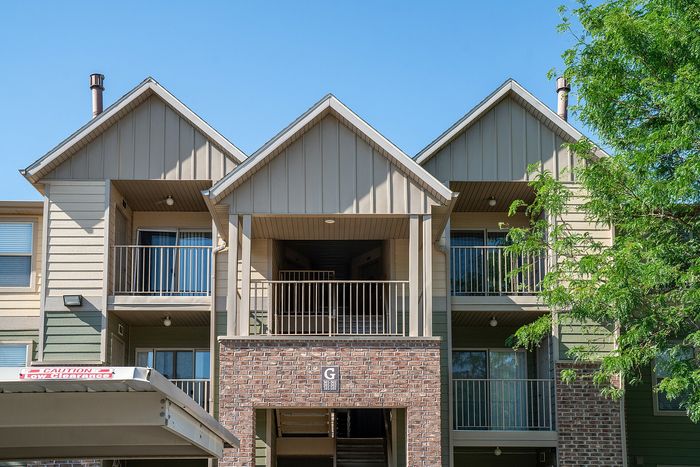 Charming apartment building with modern architectural design, featuring spacious balconies and lush greenery.