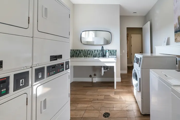Modern laundry room with sleek washers and dryers, elegant tile flooring, and a stylish backsplash.