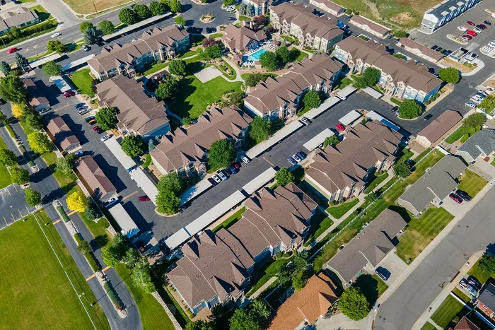 Aerial view of a modern apartment complex with lush green spaces, well-maintained landscaping, and ample parking.
