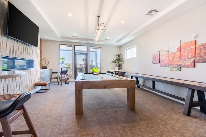 Bright and inviting recreation room with a sleek billiards table, modern decor, and large windows offering stunning natural light.