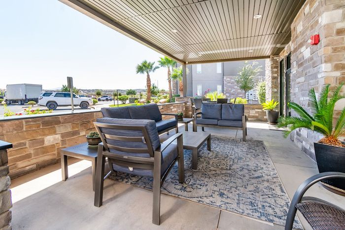 Chic outdoor patio with comfortable seating, lush greenery, and elegant stone accents, perfect for relaxing and entertaining.