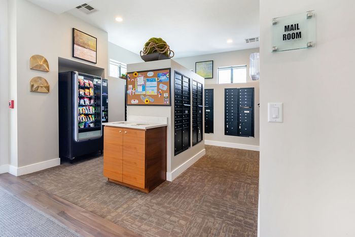 Modern mail room featuring secure lockers, vibrant decor, and convenient snack vending machine.