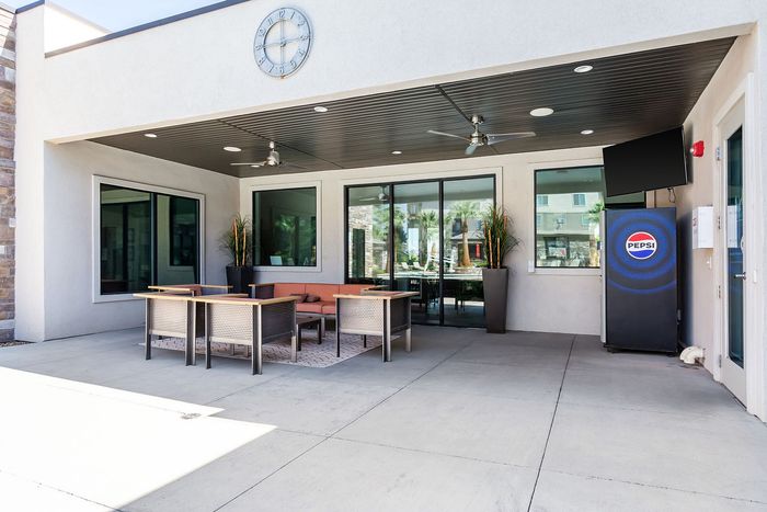 Elegant outdoor patio area with modern seating, ceiling fans, and a stylish Pepsi vending machine, perfect for a refreshing and social atmosphere.