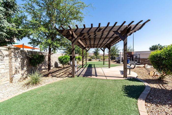 Charming outdoor space featuring a wooden pergola, lush greenery, and a peaceful setting perfect for relaxation.