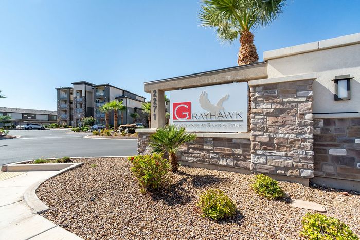 Inviting entrance of Grayhawk Apartments, showcasing modern architecture and vibrant landscaping under a clear blue sky.