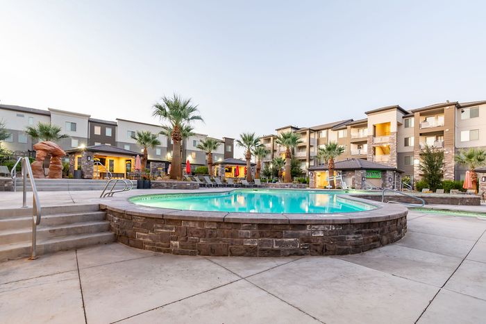 Elegant apartment complex showcasing a luxurious pool area with palm trees and modern architecture, inviting relaxation and comfortable living.