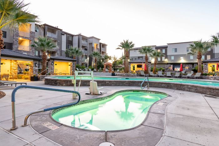 Luxurious apartment complex with stylish pool area, surrounded by modern buildings and lush palm trees, perfect for relaxation and leisure.