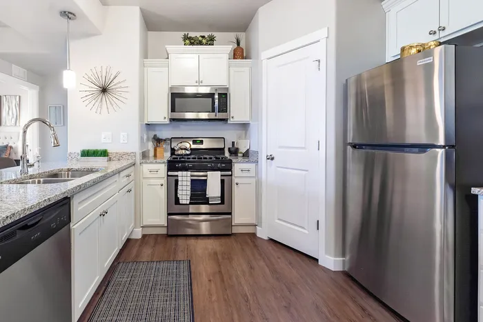 Modern kitchen with stainless steel appliances, stylish white cabinetry, and elegant granite countertops.