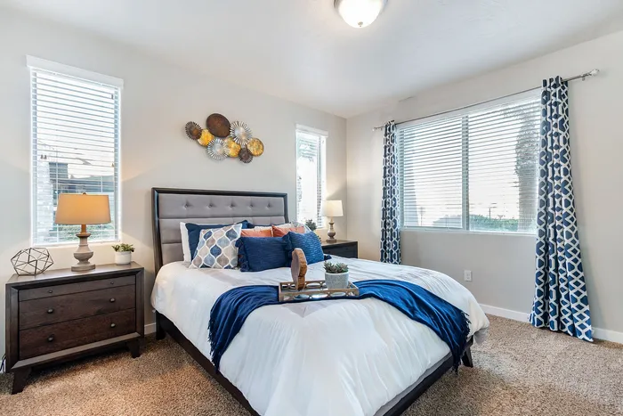 Bright and inviting bedroom with plush bed, modern decor, and natural light streaming through large windows.