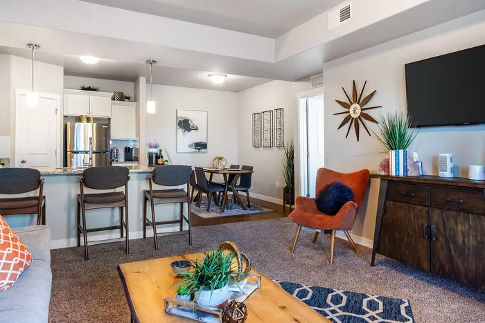 Chic living and dining area with modern decor, featuring a cozy seating setup, stylish dining table, and an open kitchen with sleek appliances and pendant lighting.