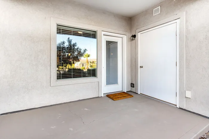 Inviting apartment entrance with a charming welcome mat, bright sunlight through blinds, and a sleek modern design.