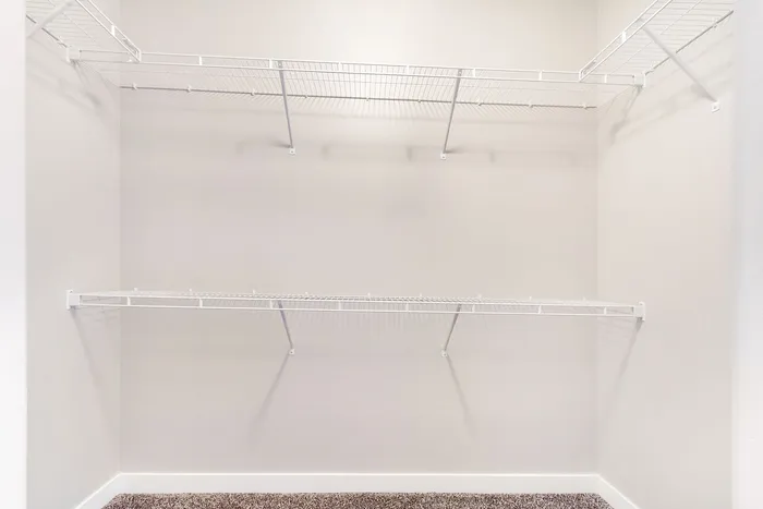 Spacious walk-in closet with sleek white shelving, perfect for organized storage and elegant design.