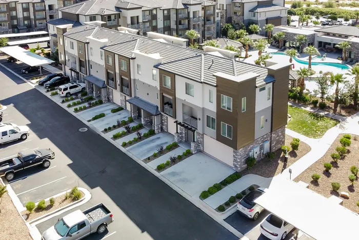 Modern apartment complex with sleek townhouses, pristine driveways, and lush landscaping. Enjoy luxury living with nearby resort-style pool and recreational spaces.