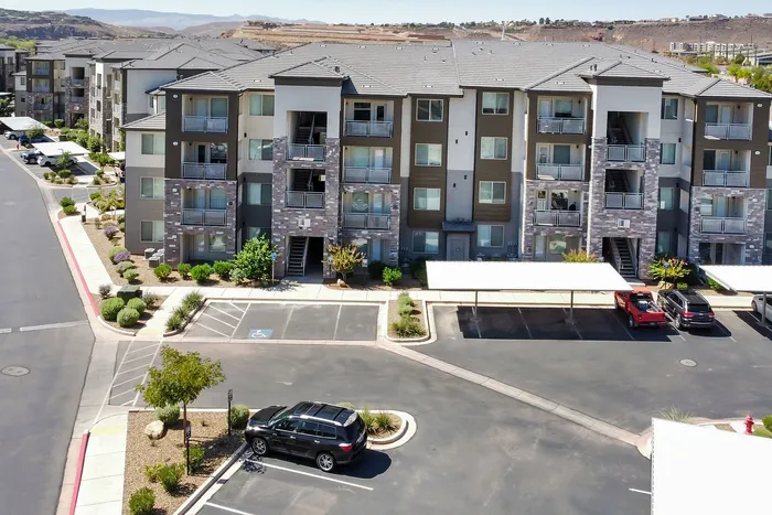 Modern apartment complex with lush landscaping, ample parking, and scenic hilltop views.