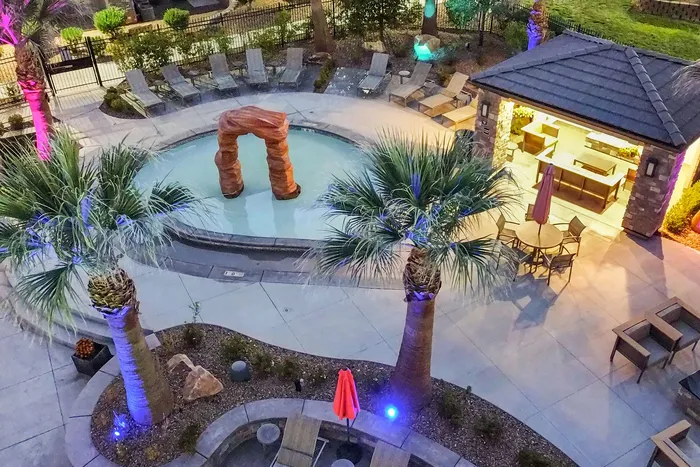 Stunning resort-style outdoor area featuring a sparkling pool, palm trees, modern lounge seating, and a chic gazebo with ambient lighting.