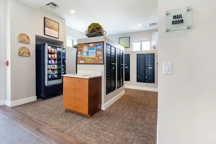 Bright mail room featuring secure mailboxes, community message board, and convenient snack vending machine.