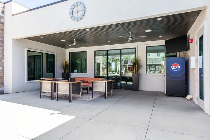 Inviting outdoor lounge area with modern seating, ceiling fans, and a convenient vending machine under a stylish covered patio.
