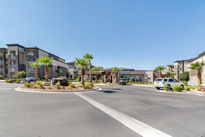 Charming apartment complex with modern architecture surrounded by palm trees and a tranquil fountain under a bright blue sky.
