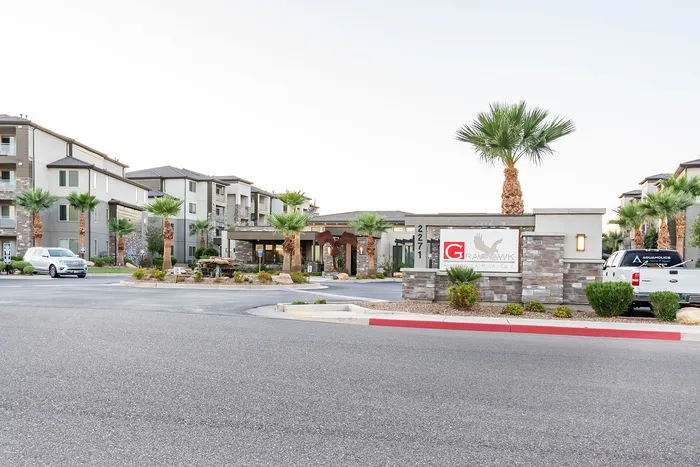 Inviting entrance to a modern apartment complex with palm trees and stone accents, featuring contemporary architecture and a welcoming atmosphere.