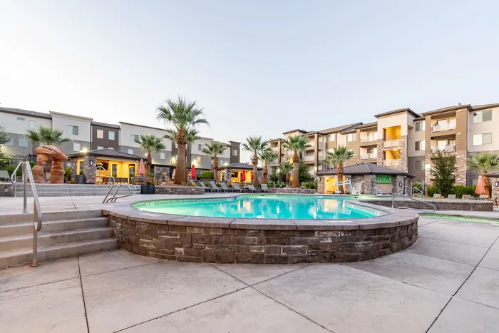 Luxurious apartment complex with a sparkling pool surrounded by palm trees and inviting modern architecture.