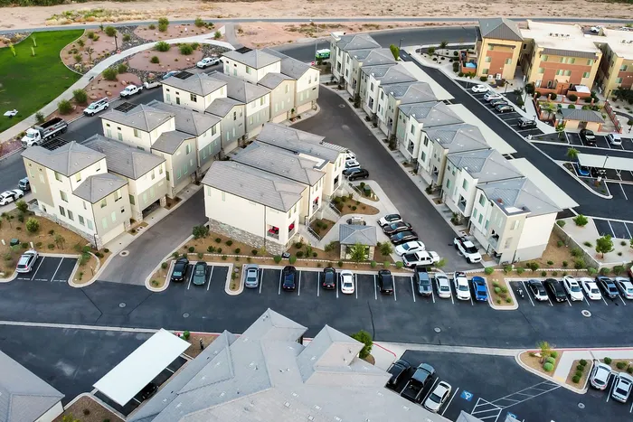Aerial view of a modern apartment complex featuring neatly arranged townhouses with ample parking and landscaped surroundings for a serene living experience.