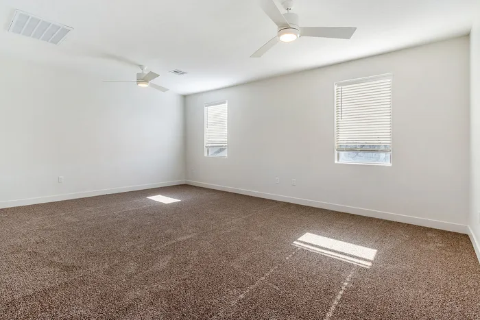 Spacious and bright room with plush carpeting and modern ceiling fans, perfect for a cozy living area or master bedroom.