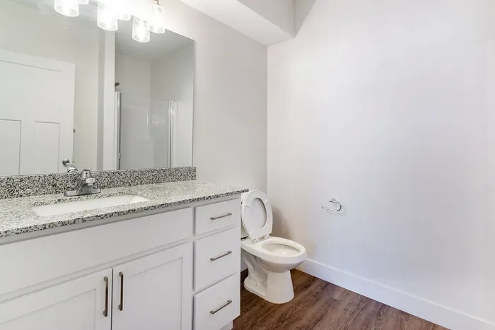 Elegant bathroom featuring a modern granite countertop, sleek white cabinets, and a contemporary light fixture.