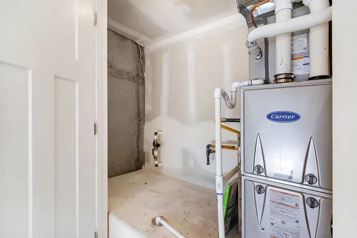 Modern utility room showcasing a sleek Carrier HVAC system with clean white walls and organized piping.